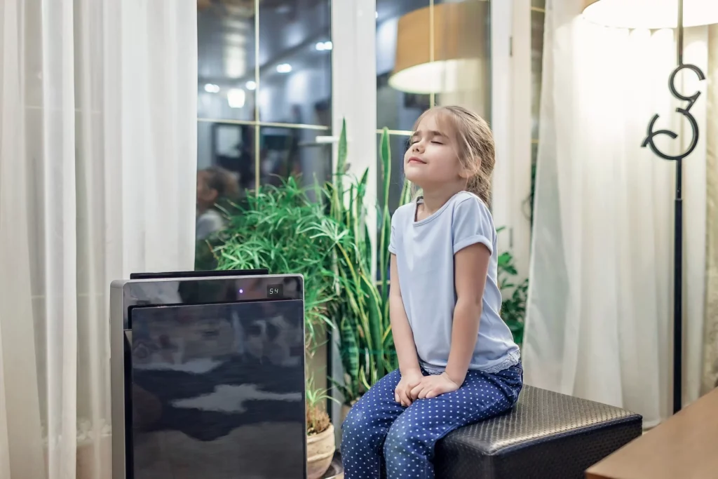 little girl breathing next to an air purifier