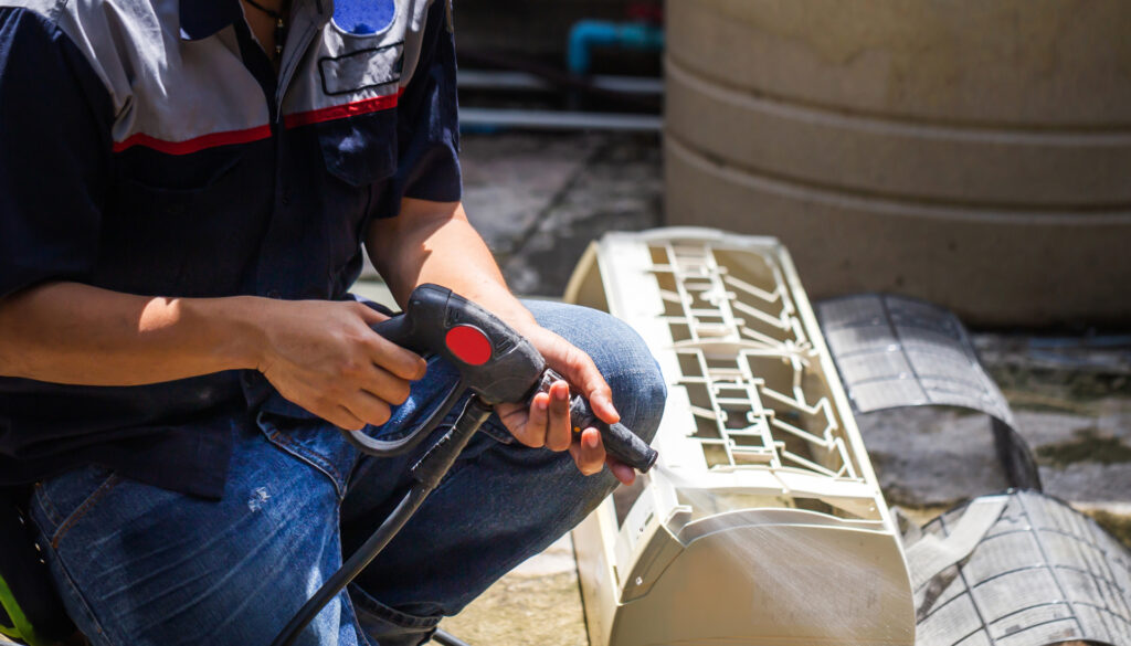 Male technician cleaning air conditioner indoors