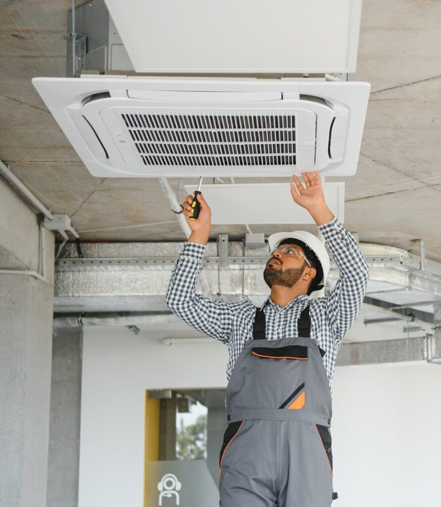 Professional technician maintaining modern air conditioner indoors.